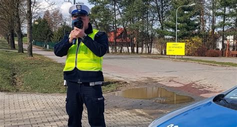 Zdjęcie przedstawiające policjanta rozmawiającego z dziećmi podczas Dnia Otwartego OSP, z widocznym radiowozem w tle