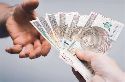 zdjęcie dłoni liczących pieniądze na tle dokumentów finansowych
