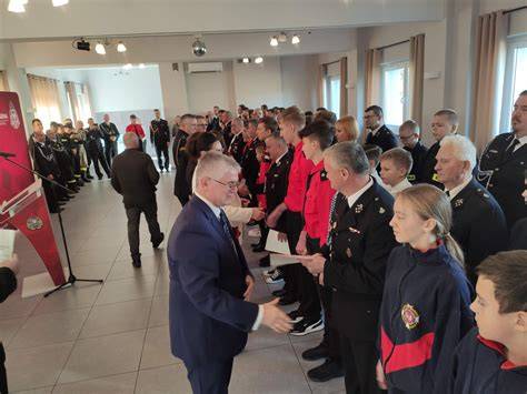 Zdjęcie przedstawiające uroczystą ceremonię otwarcia zawodów pożarniczych z udziałem młodzieżowych drużyn