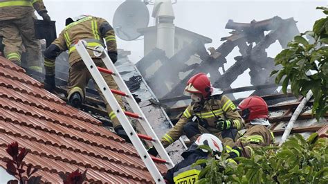 Strażacy gaszący pożar poddasza domu jednorodzinnego