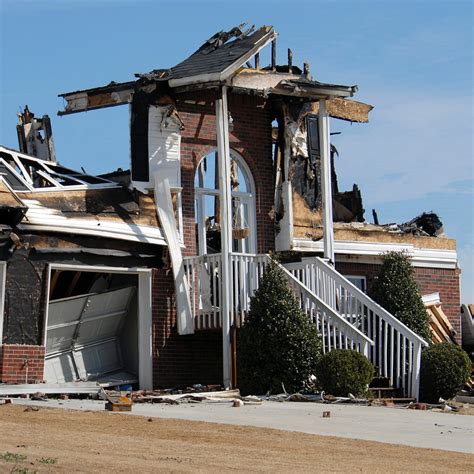 Photo of a damaged house after a fire, showing community members helping to clear debris