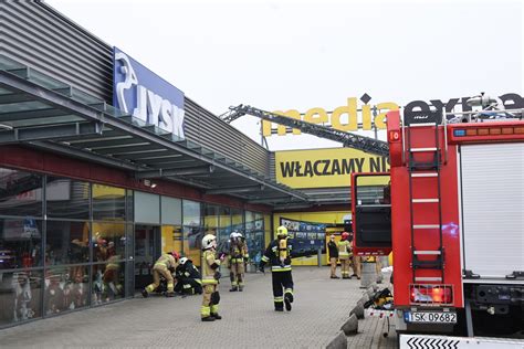 Ilustracja Smerfów w strojach strażackich, gaszących mały pożar przy użyciu magicznej wody