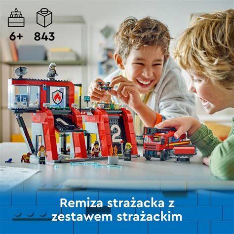 Zdjęcie przedstawiające dzieci bawiące się wykonanym z kartonu wozem strażackim.