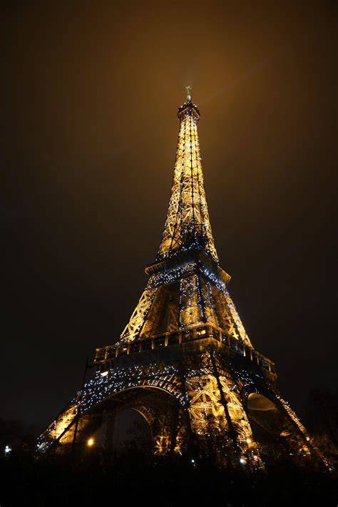 The Eiffel Tower at night with a subtle hint of smoke on the top section