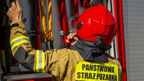 zdjęcie ilustracyjne przedstawiające pracę straży pożarnej przy zabezpieczaniu terenu wokół wysokiego obiektu