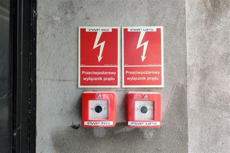 Ilustracja przedstawiająca prawidłowe oznakowanie przeciwpożarowego wyłącznika prądu (symbol „ogniska” na czerwonym tle)