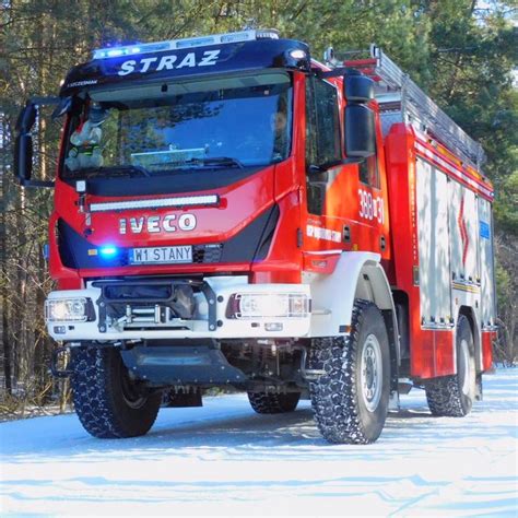 Szczegółowy widok samochodu strażackiego z widocznymi stabilizatorami, gumowymi kołami i otwieranym dachem kabiny.