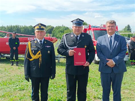 Fotografia przedstawiająca komplet umundurowania galowego strażaka OSP z widocznym identyfikatorem imiennym, czarnym krawatem i rogatywką z orzełkiem