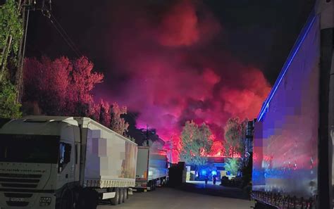 Duży pożar tartaku w nocy, widoczne płomienie i kłęby dymu