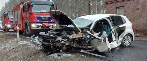Wypadek samochodu ciężarowego i osobowego na DK11, ratownicy przy wraku auta