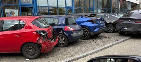 zdjęcie spalonego samochodu osobowego na tle uszkodzonych aut na parkingu osiedlowym