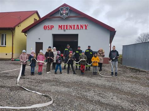 Zdjęcie ze spotkania strażaków w remizie OSP, z widocznymi gośćmi i duchownym