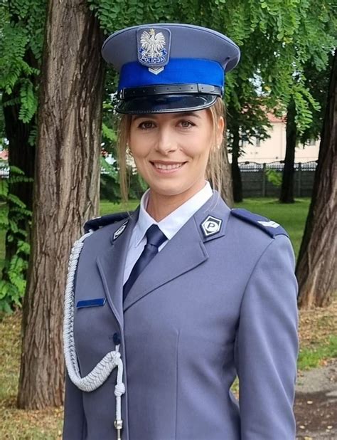 Zdjęcie strażaka w galowym mundurze, pozującego z żoną w sukni ślubnej, na tle wozu strażackiego.