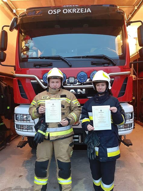 Młoda kobieta w stroju strażackim siedzi za kierownicą wozu strażackiego.