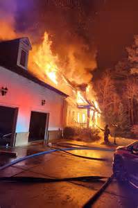 Thematic photo of a house after a fire with emergency services in the background