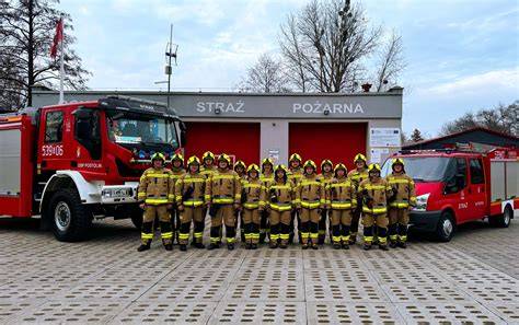 Zespołowe zdjęcie strażaków OSP na tle nowoczesnego wozu strażackiego, symbolizujące gotowość do działania