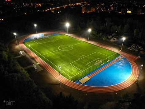 Szkolne boisko sportowe w nocy, w tle bloki mieszkalne