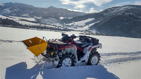 Zbliżenie na pług śnieżny i piaskarkę zamontowane na Quada Mercury