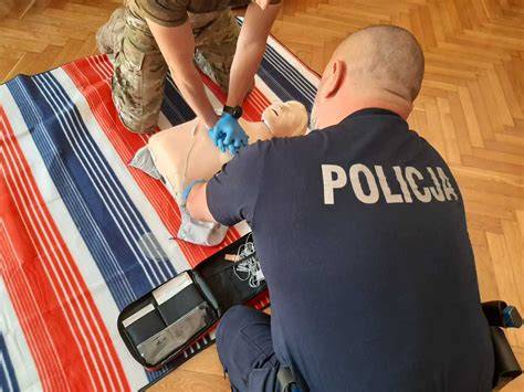 Policjant udzielający pomocy nieprzytomnemu mężczyźnie leżącemu przy drodze