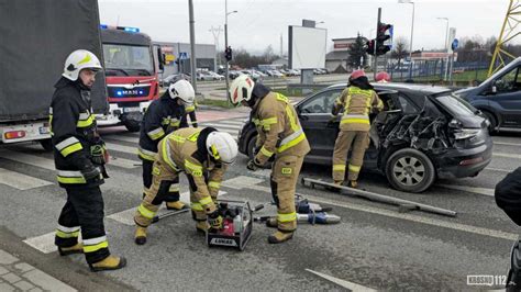 Strażacy udzielający pomocy na miejscu wypadku drogowego, w tle inne służby ratownicze