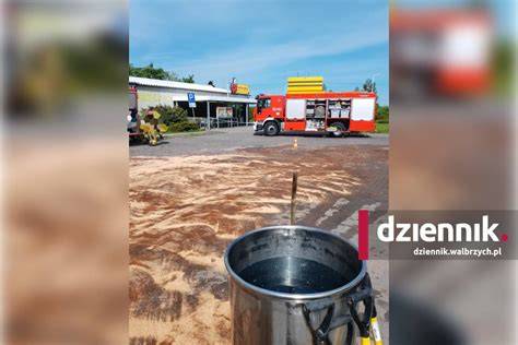 Strażacy używający sorbentu do usuwania wycieku paliwa na drodze
