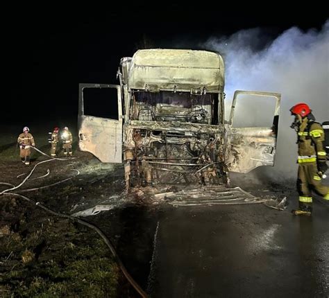 Zdjęcie płonącego samochodu na drodze, z widocznymi służbami ratunkowymi