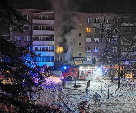 Strażacy gaszący pożar mieszkania na parterze w bloku w Bydgoszczy