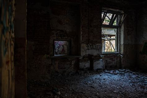 Fotografia przedstawiająca zniszczony, opuszczony budynek dawnej szkoły, z widocznymi śladami pożarów i dewastacji.