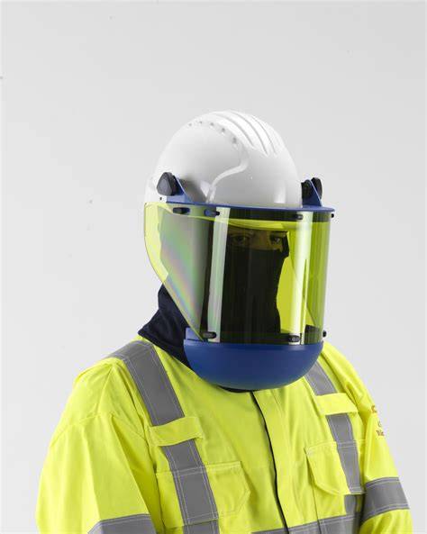 A man in protective workwear and a helmet putting on a face shield in the forest.