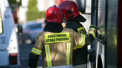 Zdjęcie przedstawiające akcję gaśniczą hali magazynowej z widocznym zadymieniem i pracującymi zastępami straży pożarnej