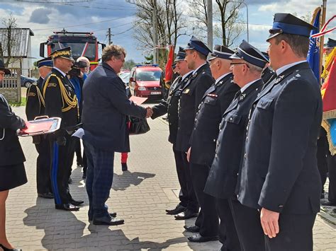 Zdjęcie przedstawiające oficjalne przekazanie kluczyków do nowych pojazdów OSP Żerkowice z udziałem władz samorządowych i strażackich, orkiestry dętej w tle.