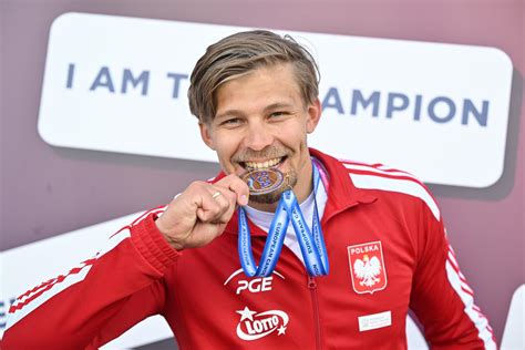 Zwycięski Rafał Bereza z medalem Mistrzostw Europy FCC, tło: tor przeszkód lub flaga Polski