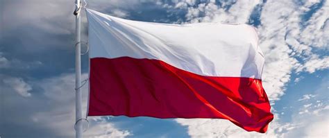Zdjęcie flagi OSP z klamrami do masztu na tle błękitnego nieba