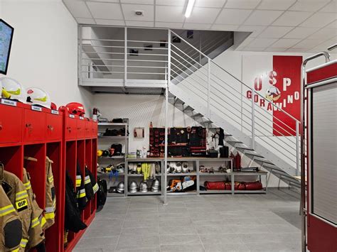 Zdjęcie przedstawiające nowoczesne wyposażenie remizy strażackiej, w tym szafy na odzież, sprzęt i urządzenia.