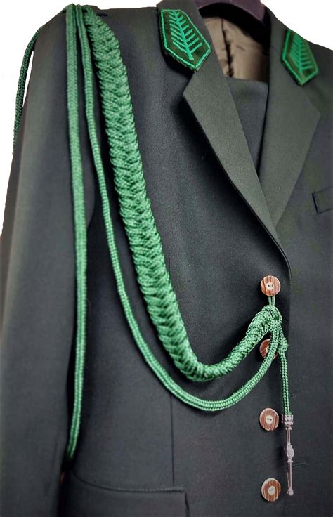 Zbliżenie na detale munduru galowego: pagon z miejscem na sznur, guziki mundurowe, emblemat związkowy na klapie.