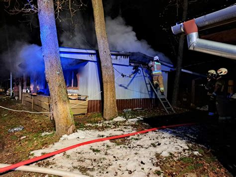 Strażacy gaszący pożar drewnianego domku letniskowego