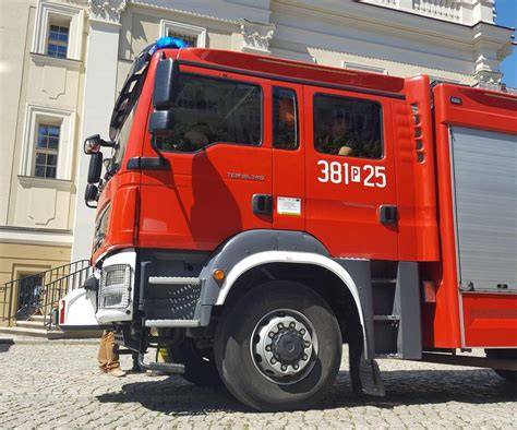 Zdjęcie przedstawiające akcję gaśniczą w Starej Dąbrowie, widoczne wozy strażackie i dym