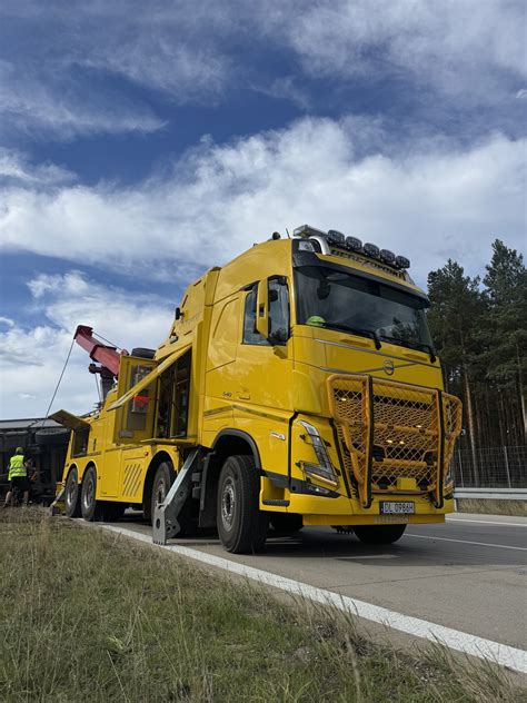 Zdjęcie miejsca zdarzenia po pożarze, ukazujące zniszczone pojazdy oraz uszkodzoną wiatę fotowoltaiczną.