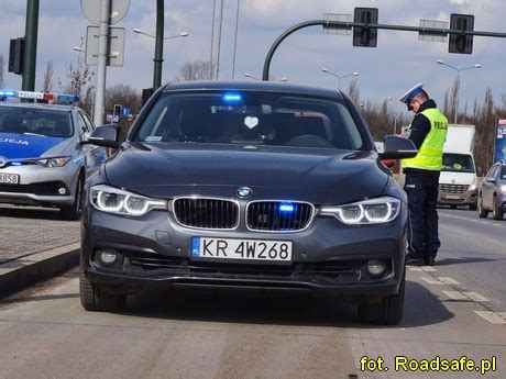 Płonący policyjny radiowóz BMW na drodze w Toruniu, w tle wóz strażacki
