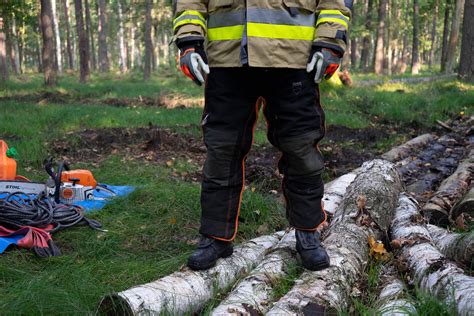 Strażak podczas usuwania powalonego drzewa, widoczne spodnie ochronne