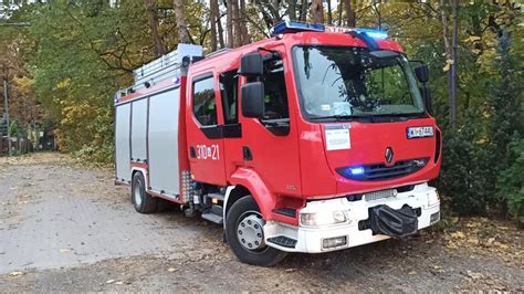 Strażak podczas usuwania powalonego drzewa na jezdni, z widocznym wyposażeniem ochronnym