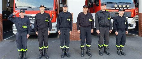 Strażacy i policjanci przed zadymionym budynkiem