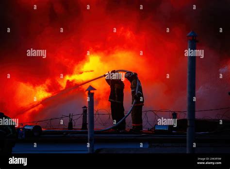 Thematic photo of firefighters extinguishing a blaze in a tenement building roof at dawn