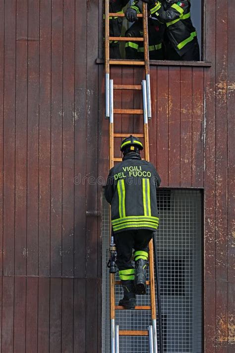 A photo of firefighters on a ladder with Mikołaj waving to children in hospital windows