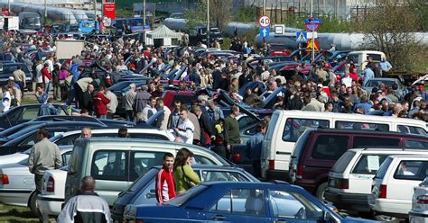 Zdjęcie tłumnej giełdy samochodowej w Polsce, z widocznymi rzędami samochodów i kupującymi