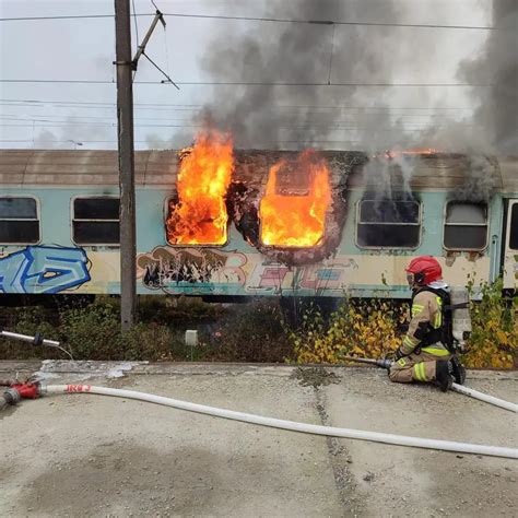 Strażacy gaszący pożar wagonu kolejowego na torach, widoczny sprzęt ratowniczy