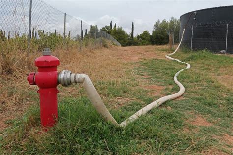 Thematic photo of a fire hose connected to a pump, in a rural or domestic setting