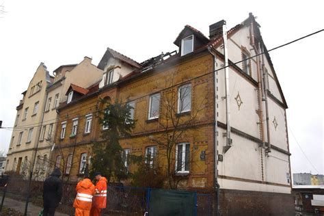 Fotografia kamienicy po pożarze, z widocznymi uszkodzeniami dachu i pierwszego piętra