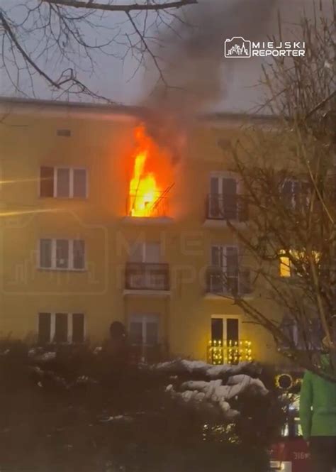 Zdjęcie strażaka gaszącego pożar z okna na piętrze budynku mieszkalnego w nocy