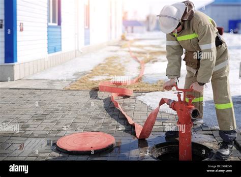 Thematic photo of a firefighter connecting a hose to a red above-ground hydrant